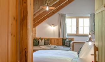 A cozy bedroom with wooden ceilings and a large bed. Light streams through the window, creating an inviting atmosphere.