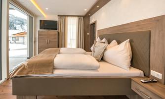 A modern bedroom with a large bed and clean lines. The combination of wood and neutral colors creates a cozy atmosphere.