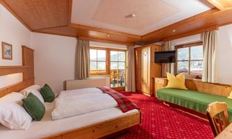 A cozy bedroom with a double bed and a single bed. The warm wooden furniture creates an inviting atmosphere.