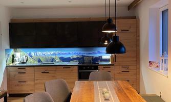 A modern dining room with a wooden desk and comfortable chairs. In the background is an elegant sideboard with decorative lighting.