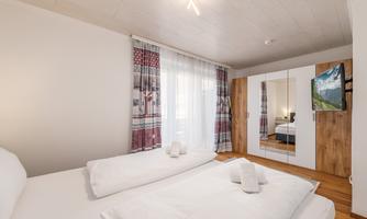 A cozy bedroom with two single beds and modern furniture.  
Large windows provide plenty of natural light and a pleasant atmosphere.