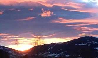 A beautiful sunset over the mountains. The sky is drenched in warm colors like orange and purple.