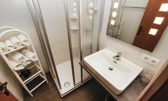 A modern bathroom with a shower and a sink. Towels are neatly arranged on a rack.