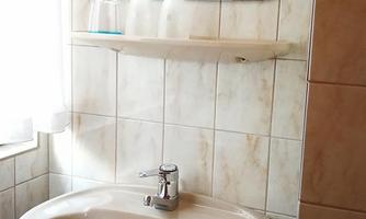 A bathroom with a round sink and a mirror. Soft colors and a bright window create a friendly atmosphere.