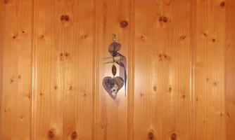 A wooden door with a heart-shaped decoration hangs on it. Above the door, a round clock is mounted.