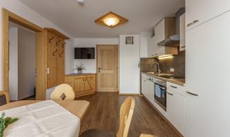 A modern kitchen with light wood and white furniture. The dining area is simply and invitingly designed.