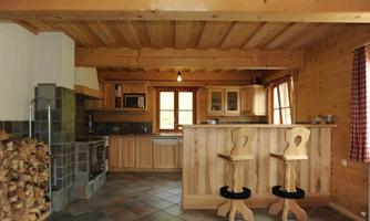 A cozy wooden kitchen with modern appliances and a small dining area. The room has large windows that let in plenty of light.