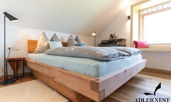 A modern bedroom with a wooden bed and comfortable pillows. Natural light filters through the window, creating a cozy atmosphere.