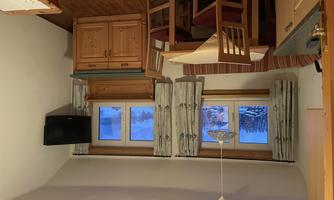A cozy kitchen with a dining area and a television. The windows offer a view of the snow-covered landscape outside.