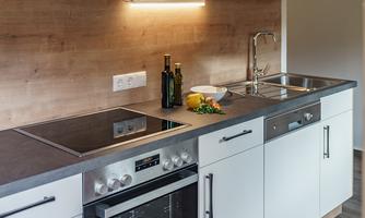 A modern kitchen with bright cabinets and a gray countertop. It is equipped with a stove, an oven, and a sink, ideal for meal preparation.
