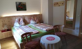 A cozy bedroom with two single beds and wooden paneling. A round table and a mirror complement the inviting atmosphere.