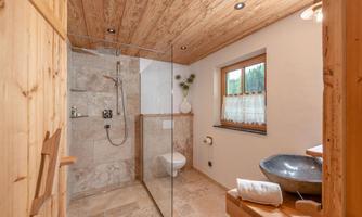 A modern bathroom with a glass shower and a stylish wash basin. Natural wooden elements and windows create a bright, inviting atmosphere.