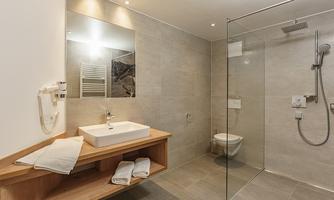 A modern bathroom with a glass shower and an elegant sink. The walls are painted in... neutral tones, and there are fresh towels on the shelf.