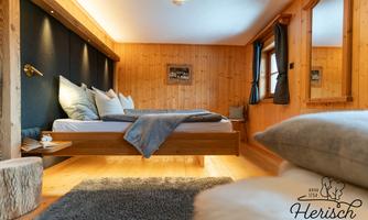 A cozy bedroom with wooden paneling and a modern bed. The warm colors and the light create an inviting atmosphere.