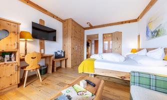 A cozy room with wooden interior and a large bed. There is a television, a table, and cozy decorations.
