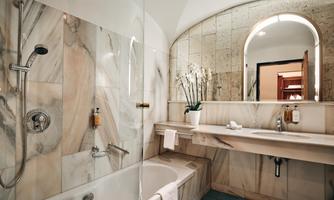 A modern bathroom with marbled walls and an elegant bathtub. The space is bright and inviting.