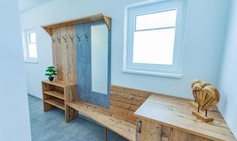 A modern changing room with wooden shelves and a mirror. Bright walls and large windows provide plenty of light.