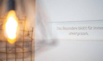 A glowing light bulb in a wire frame, next to clear text on a wall. The text reads: "The special remains forever unforgettable."