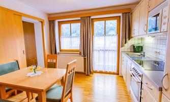 A bright and inviting kitchen with a dining table and chairs. Large windows let in plenty of natural light and offer a view outside.