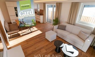 A modern living room with a bright, inviting atmosphere. In the background, there is a map with the text "Schladming-Dachstein."