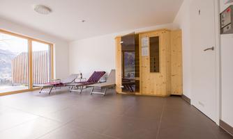 A bright wellness area with a wooden sauna and loungers. Large windows let in plenty of daylight and offer a beautiful view.