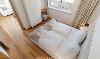A bright and modern bedroom with a double bed and a friendly atmosphere. The room features hardwood floors and large windows that let in plenty of light.