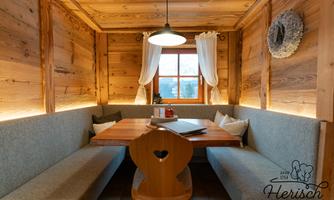 A cozy dining area made of wood with a rustic atmosphere. The table is set with a small decoration in the center, and the lighting creates a warm mood.