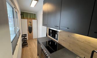 A modern kitchen with dark cabinets and a wood look. It features a stove and a stone countertop.