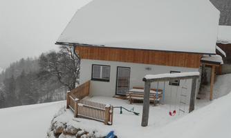 A lonely house in a winter landscape, surrounded by snow. The surroundings are quiet and picturesque with snow-covered trees in the background.