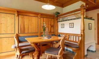 A cozy dining area with wooden furniture and a warm atmosphere. The walls are paneled with wood and the decoration is simple and inviting.