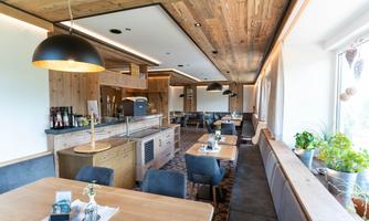 A modern restaurant with warm wooden interiors and cozy tables. The large glass front lets in plenty of light and creates an inviting atmosphere.