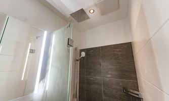 A modern shower with a glass partition and elegant tiles. The lighting creates a pleasant atmosphere.