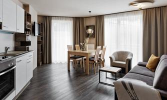 Modern apartment with open kitchen and dining area. Bright windows create a friendly atmosphere.