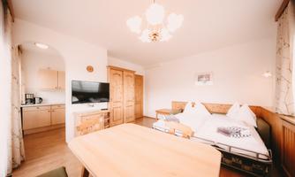 A cozy room with a double bed and a dining area. The kitchen is integrated into the room and well-equipped.