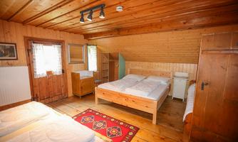 A cozy bedroom with wooden paneling and two beds. The decor is rustic and inviting.