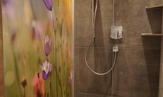 A modern shower with a blooming flower wall. The floor is tiled in gray, and the shower fixture is clearly visible.