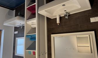 A modern bathroom with two sinks and a large mirror. Towels in various colors are neatly arranged on a shelf.