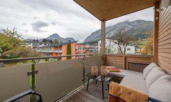 A cozy balcony with a view of mountains and a blanket of clouds. On the balcony, there are two baskets and a blanket that invite relaxation.