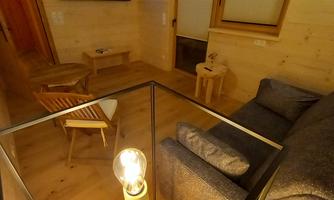 A cozy living space with wooden paneling and modern lighting. The pull-out couch and a large television characterize our living room on the first floor.