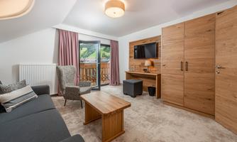 A modern room with a cozy sofa and a table. The room has large windows that offer a view outside.