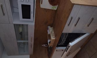 A modern kitchen with a wooden countertop and white cabinets. The dishwasher is open, and a microwave is also available.