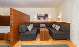A modern room with a cozy seating area and a wooden partition wall. The room has bright colors and a warm, inviting style.