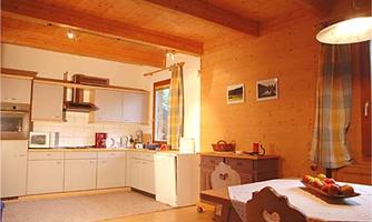 A cozy kitchen with modern appliances and warm wood decor. Fresh fruit and inviting details are on the table.