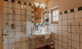 A modern bathroom with a glass shower and a sink. The wooden floor and tiles create a warm atmosphere.