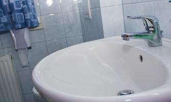 A modern sink in a bathroom. The walls are tiled and there is a shower curtain in the background.