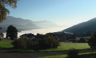 A picturesque mountain landscape with high mountains and thick mists in the valley. The clear view is indicative of a sunny day.