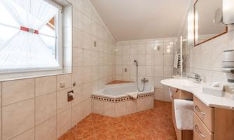 A modern bathroom with a bathtub and a sink. Large windows provide plenty of daylight.