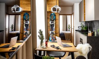A modern home with a wooden and designer dining area. In the background, snowboards and plants can be seen.