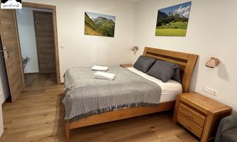 A modern bedroom with a wooden bed and cozy bedding. Pictures of landscapes hang on the walls.