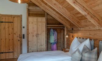A cozy bedroom with wooden ceilings and a classic design. The room features a double bed and a wardrobe.